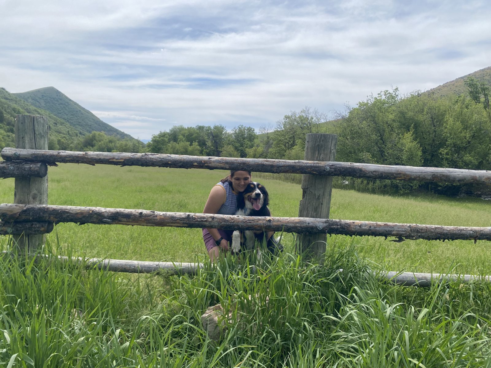 Lillie and a dog in an open meadow with the Cache Valley foothills behind them